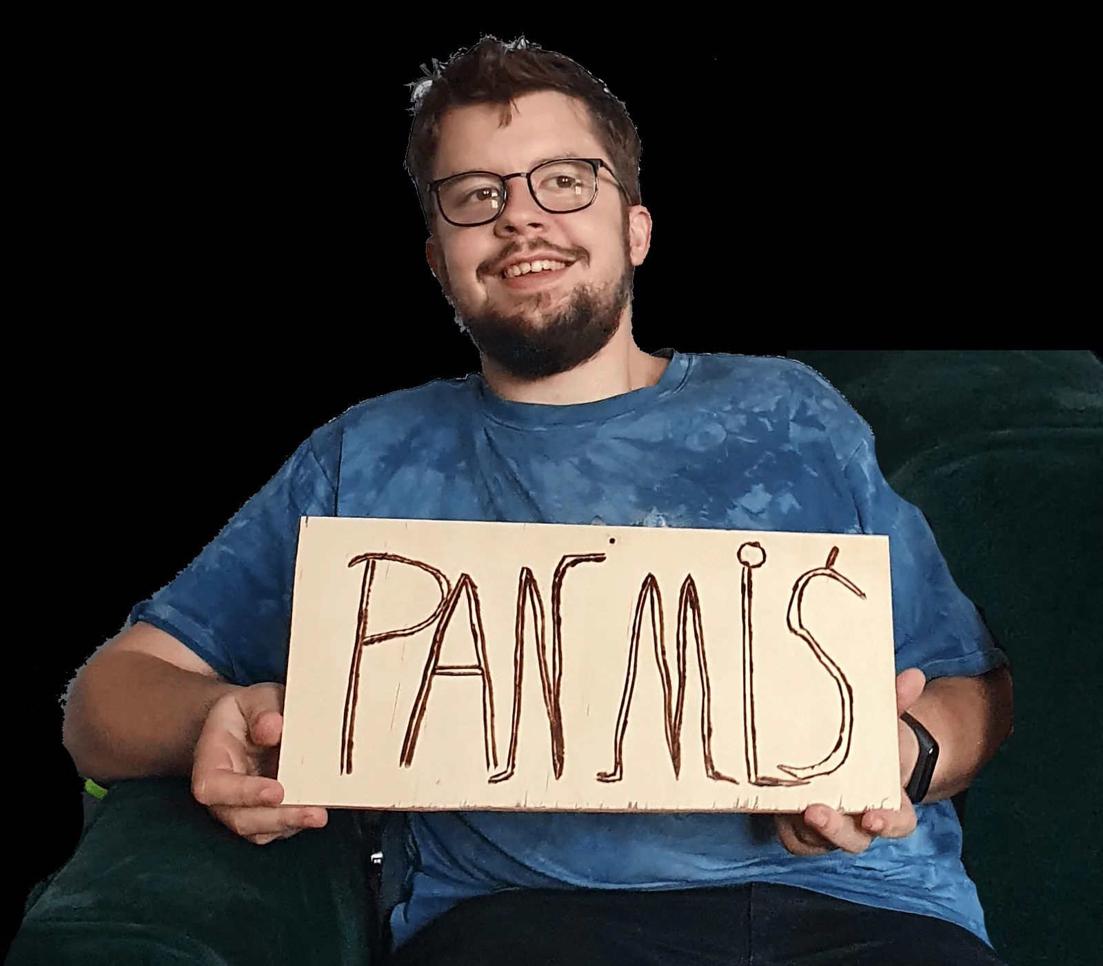 Michał Walczyk sits in an armchair holding a board with the burnt inscription PAN MIŚ