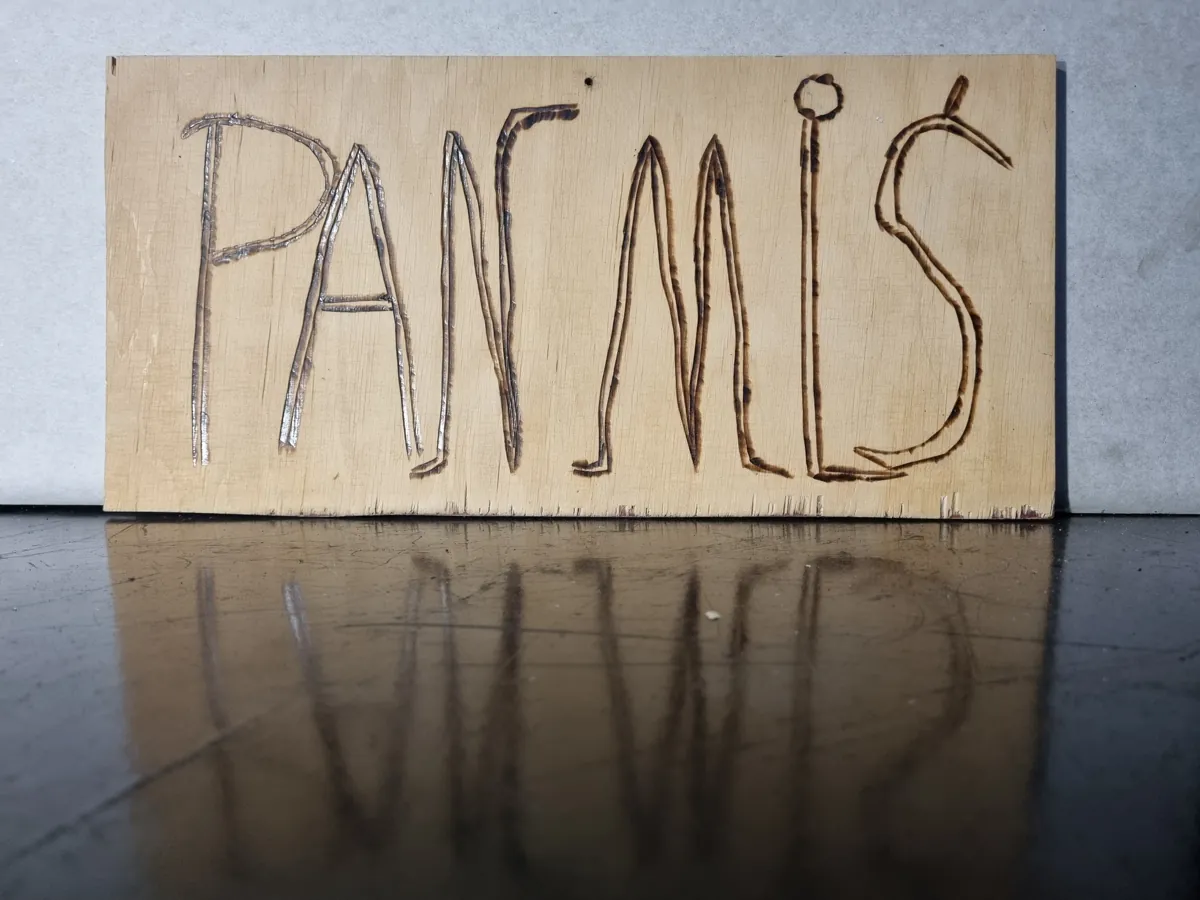 A light wooden board with the hand-burnt inscription PAN MIŚ