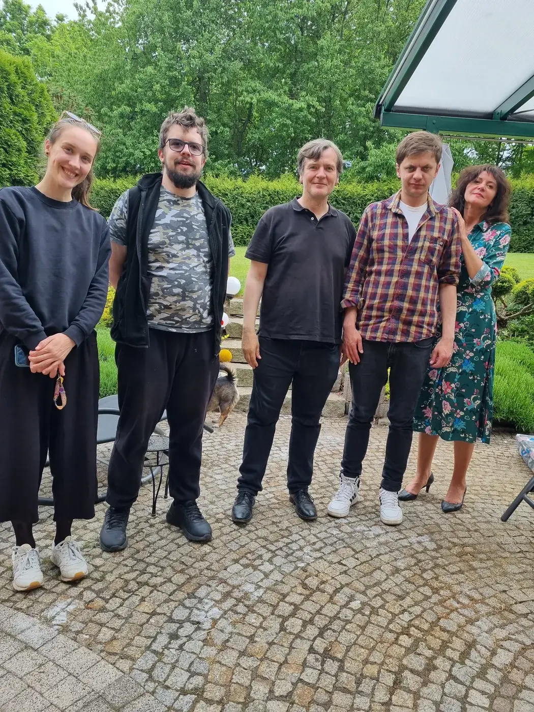 Pięć osób pozuje do wspólnego zdjęcia w ogrodzie przed pracownią