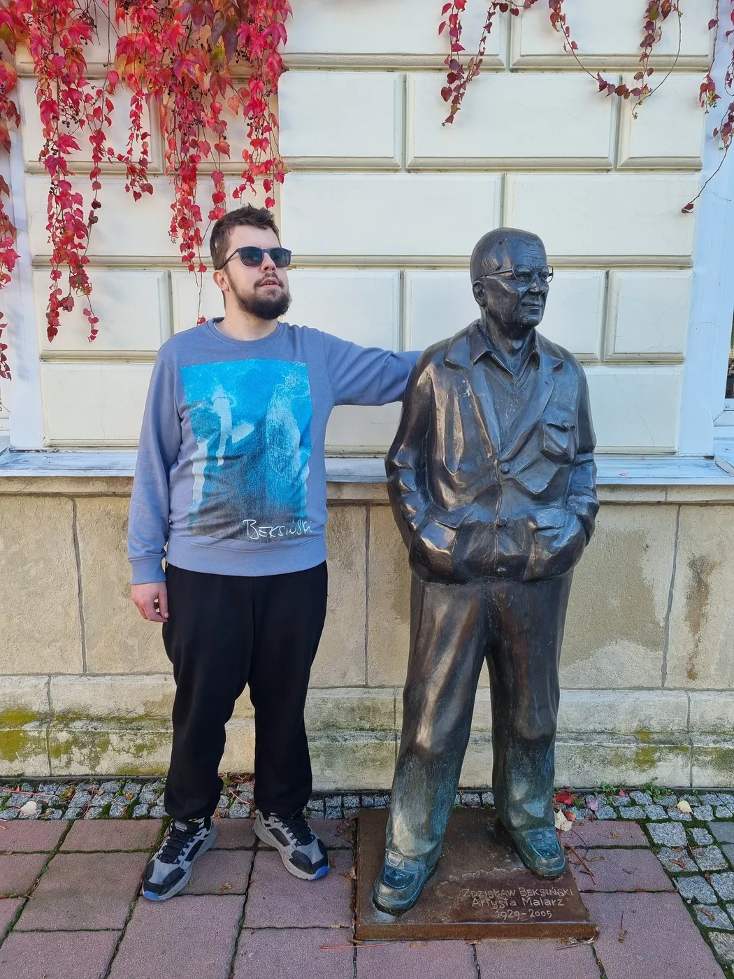 Michał Walczyk stoi obok pomnika Zdzisława Beksińskiego w Sanoku